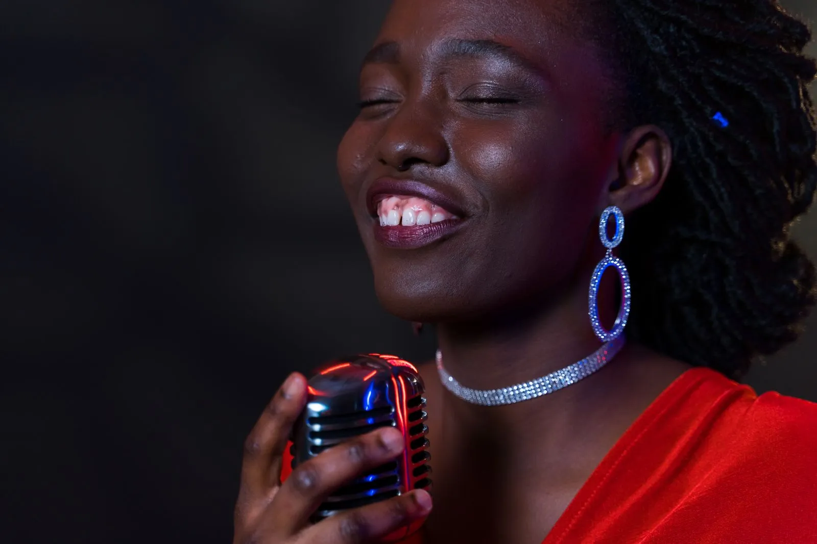 A joyful female vocalist passionately sings into a vintage microphone under vibrant lighting.